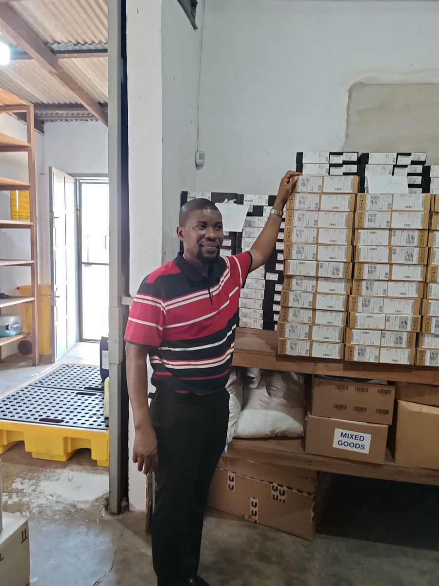 Hankaka team member beside IT hardware staged and labelled for deployment in the secure Accra warehouse
