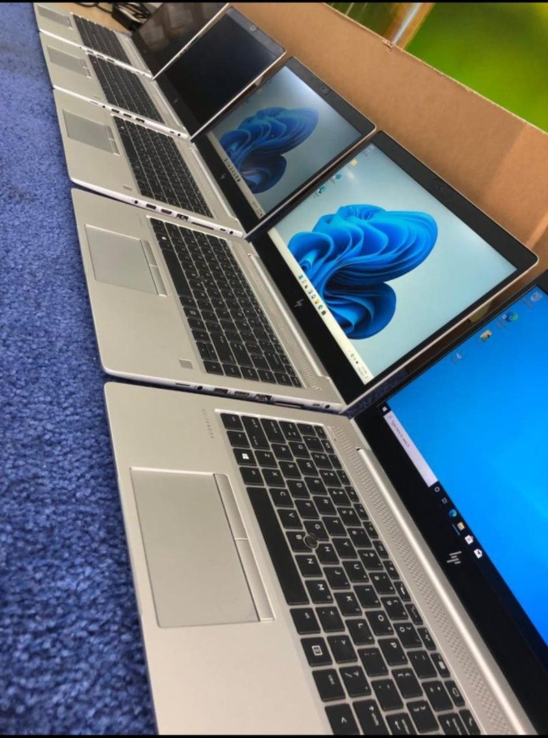 Une rangée d’ordinateurs portables HP EliteBook ouverts sur un banc de préparation, chacun en cours d’installation du système d’exploitation.